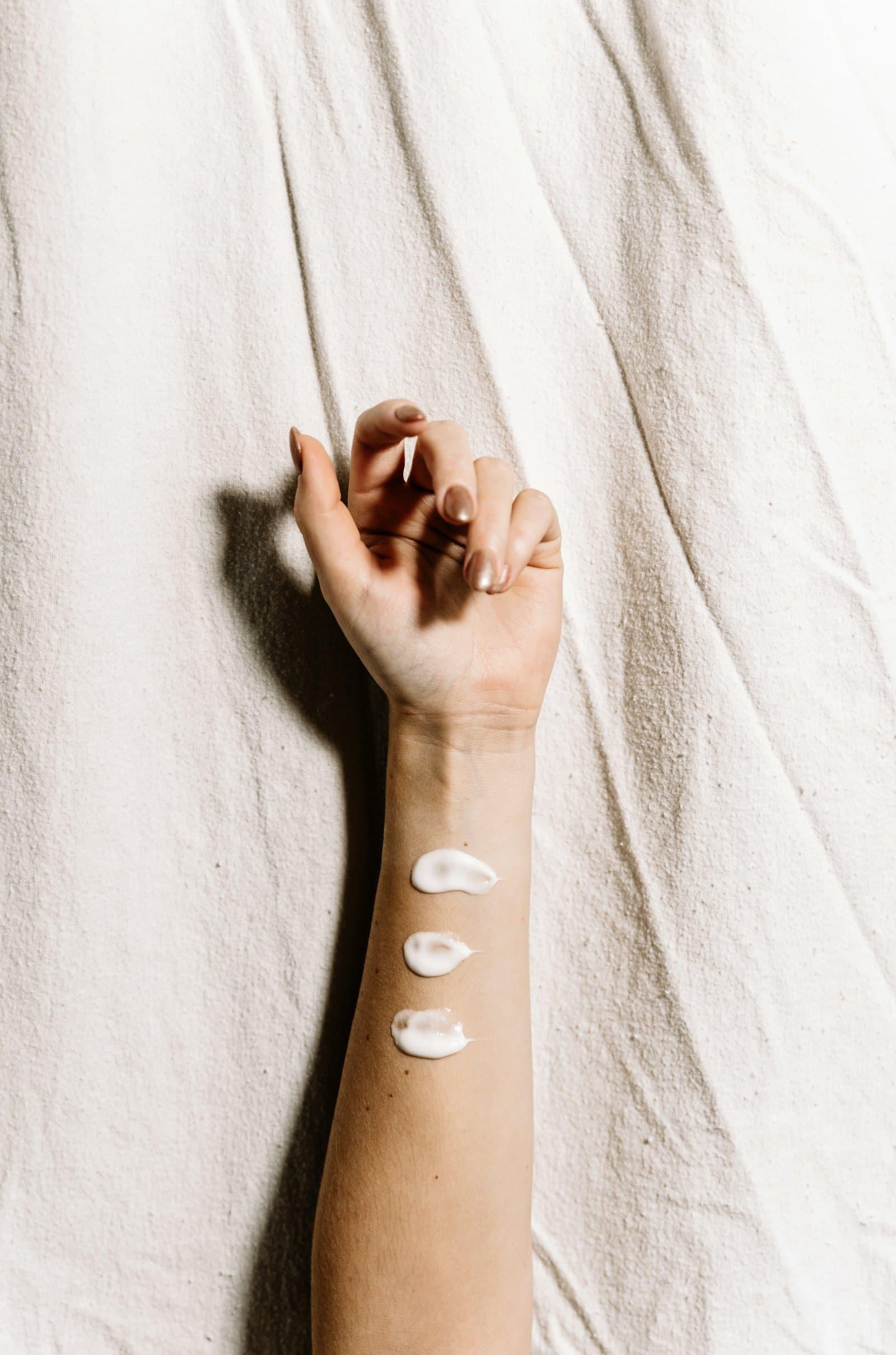 Two swatches of moisturiser resting on linen